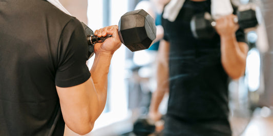 Man voert een biceps curl met een dumbbell uit voor de spiegel in de sportschool. Effectieve arm oefening voor spiergroei en kracht.