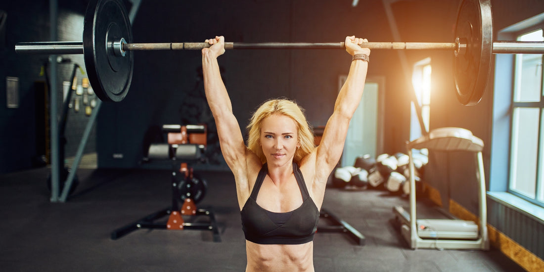 Sportvrouw doet een barbell overhead press in de gym