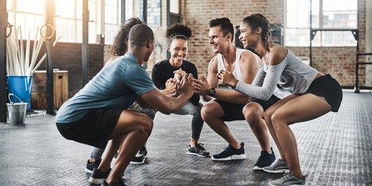 Groepje mensen die samen in de gym een squat doen voor glutes activatie